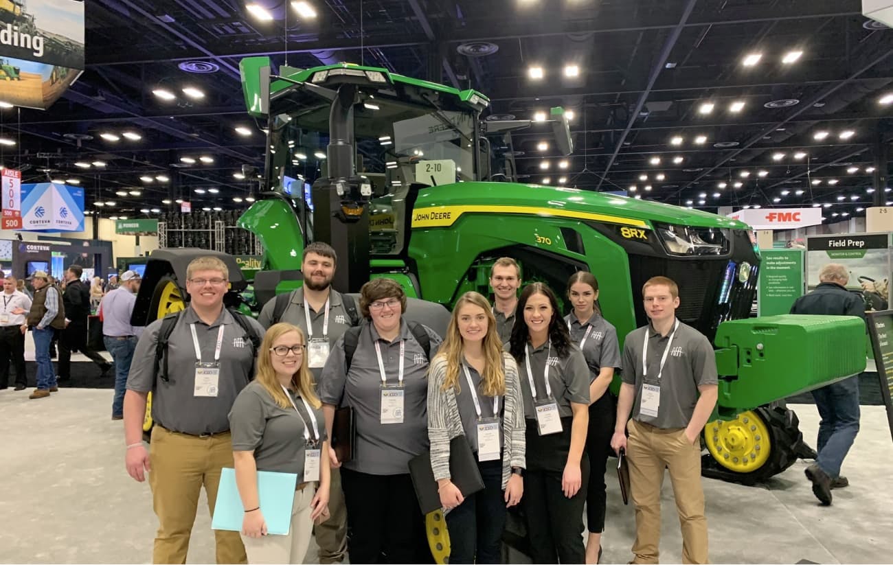 Students standing in front of tractor at conference